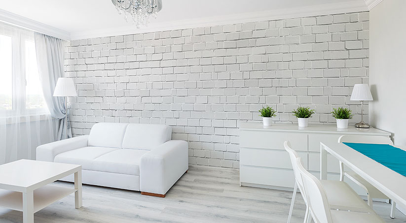 Minimalistyczny salon, utrzymany w skandynawskim klimacie, z fototapetą imitującą kamienną, bieloną ścianę